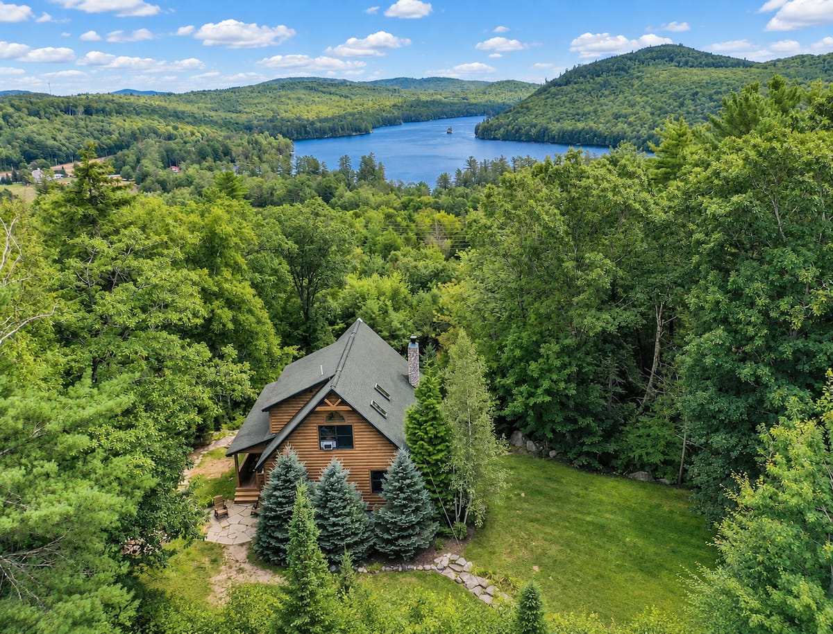 A wood cabin above a lake and mountains in Bryant Pond, Maine, part of the Premier STR collection