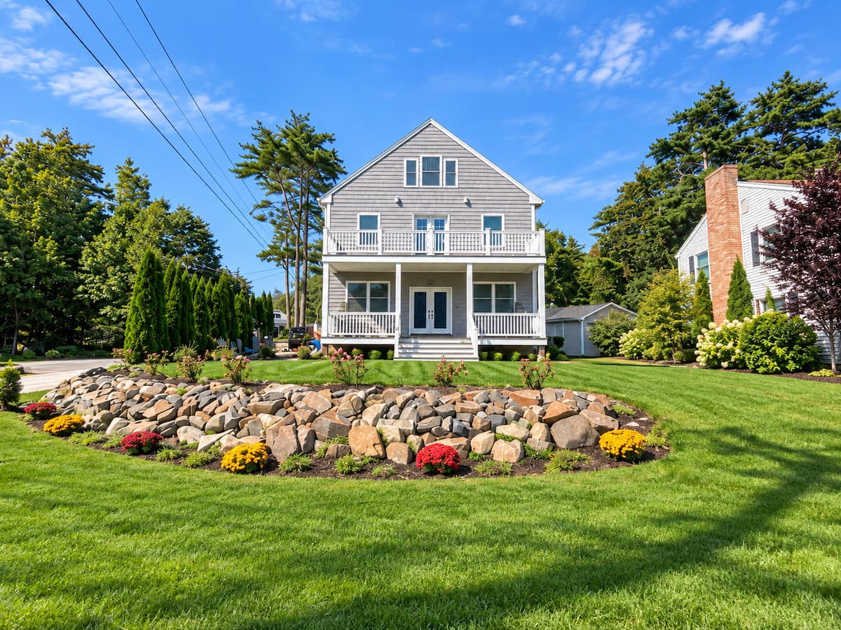 Grey shingle-style custom coastal home with a porch in York, Maine